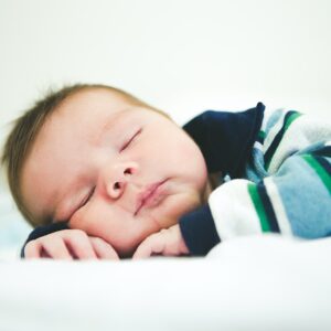baby in black and white stripe shirt lying on bed